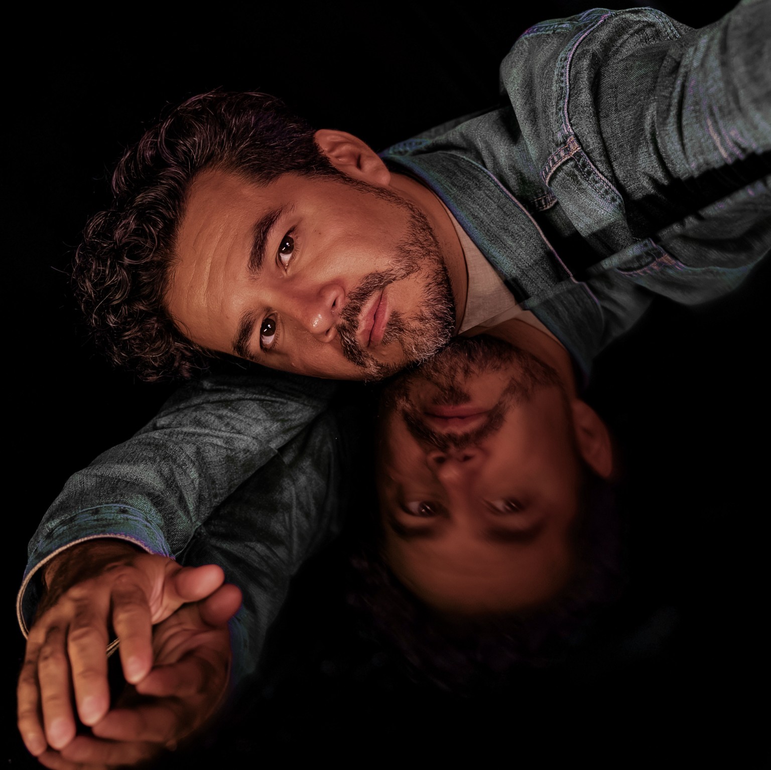 Chris Medina lying beside his reflection against a black background
